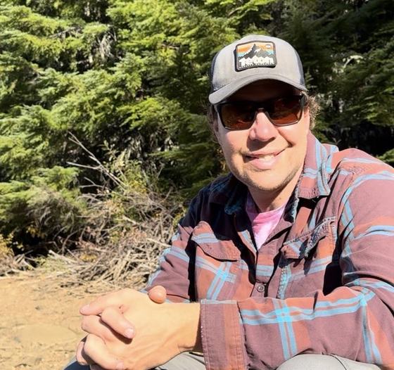 Kris Klug, owner of Under Pressure Mt. Hood, outdoors in the trees near Mt. Hood.